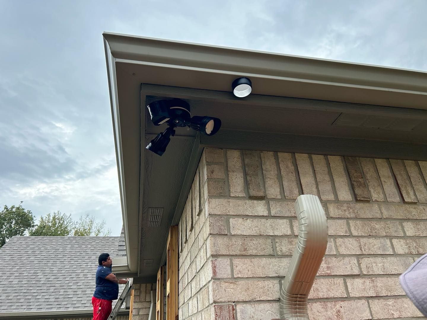 A man is working on the roof of a brick house.