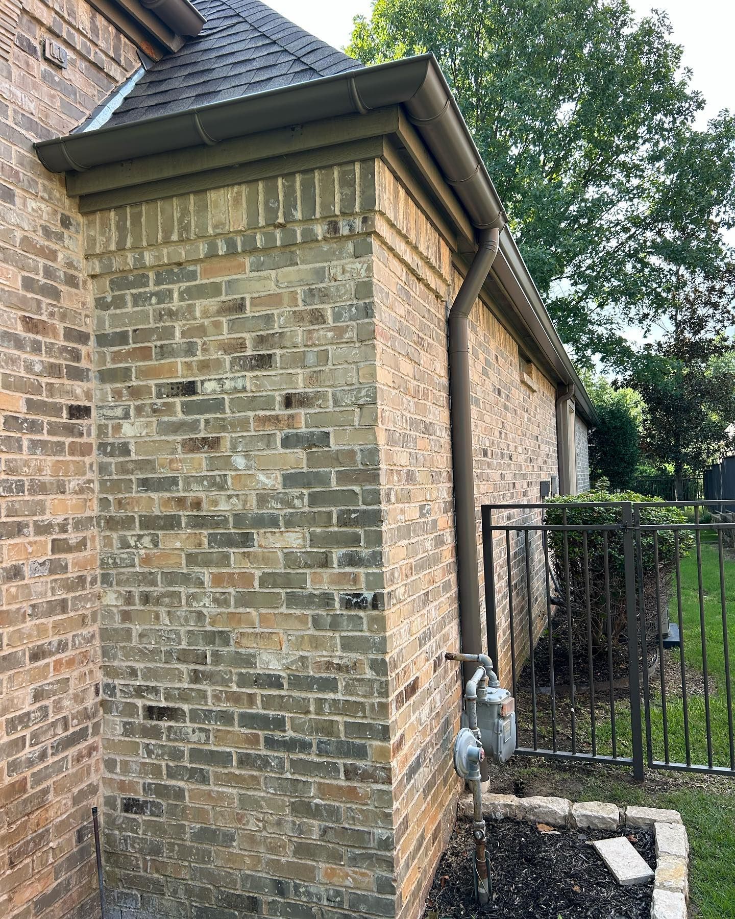 A brick house with a gutter on the side of it.