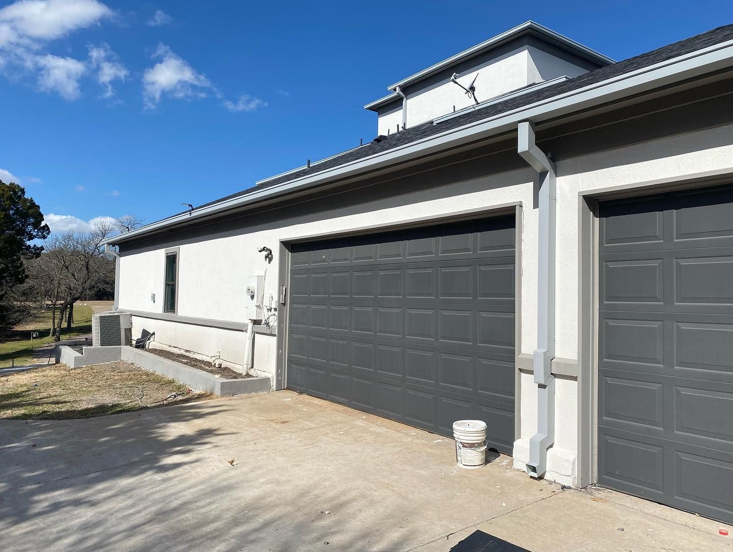 There are two garage doors on the side of a house.