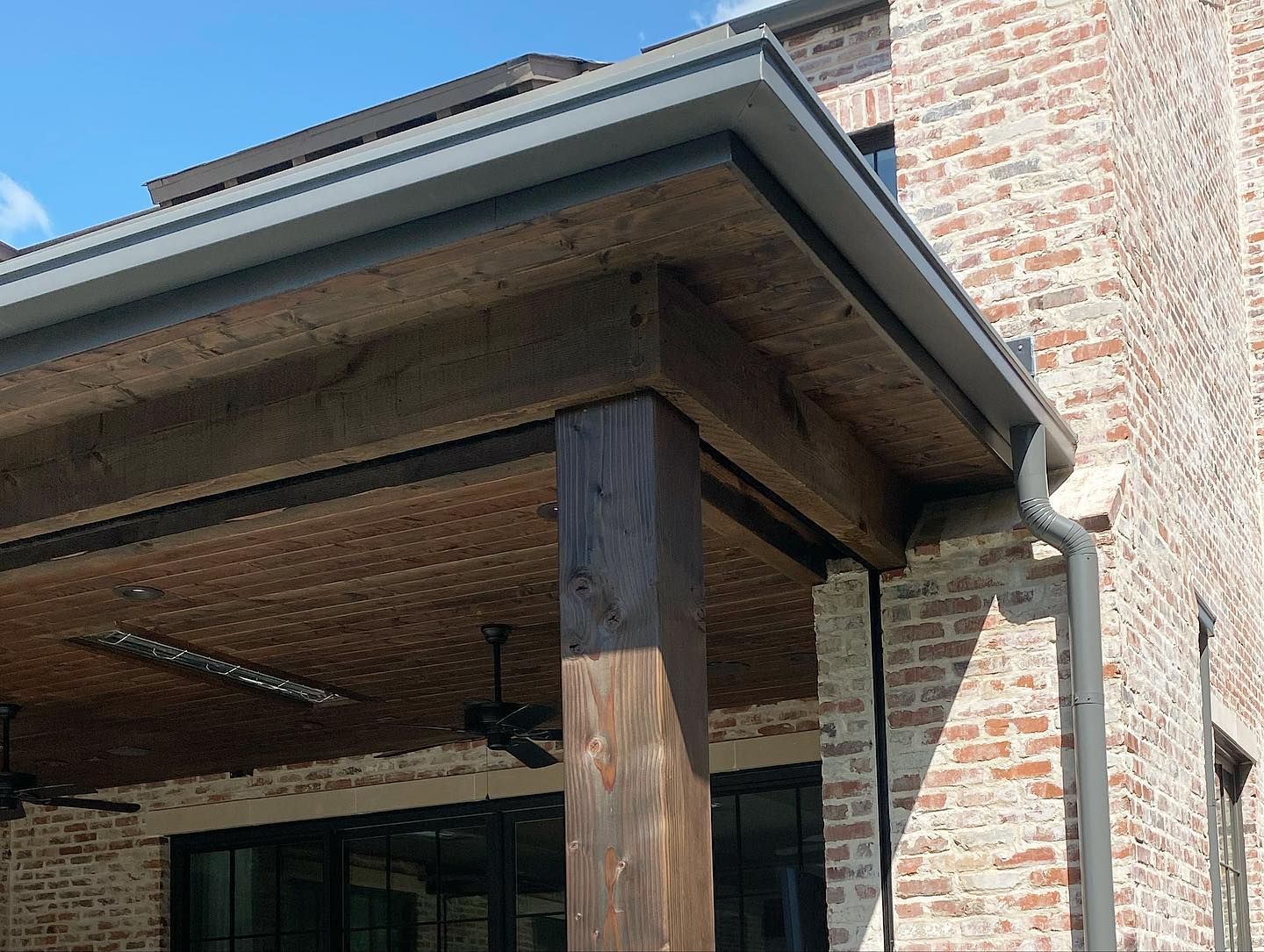 A brick building with a wooden porch and a ceiling fan.