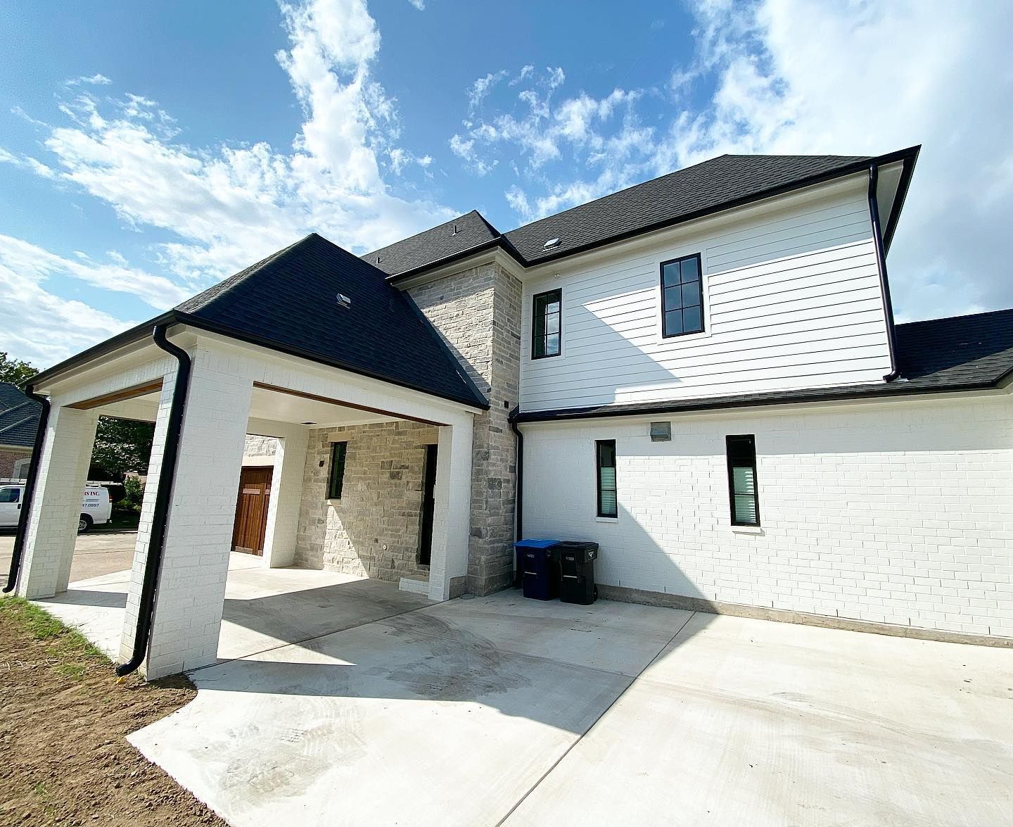 A large white house with a black roof and a driveway.