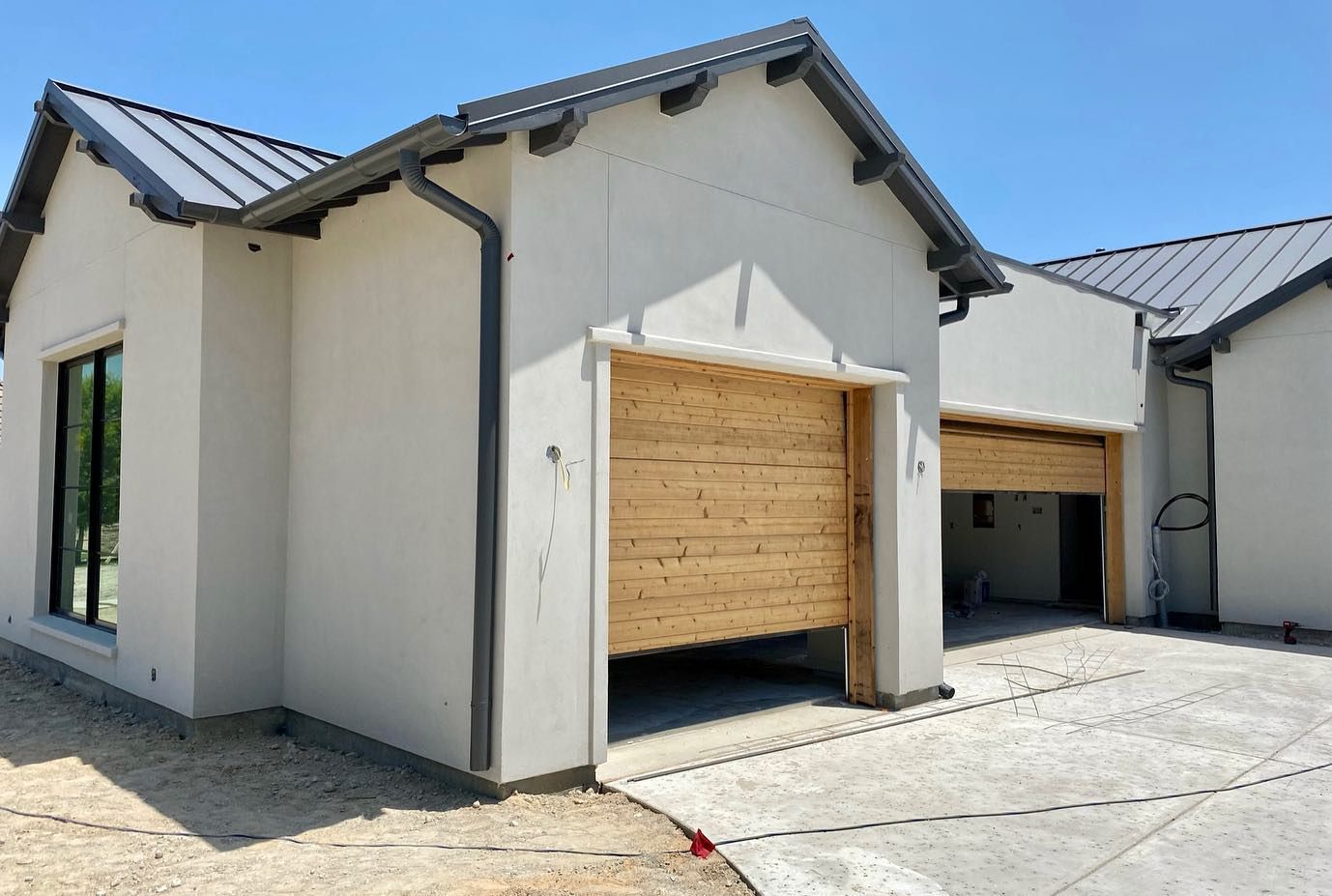 A white house with a wooden garage door is under construction.