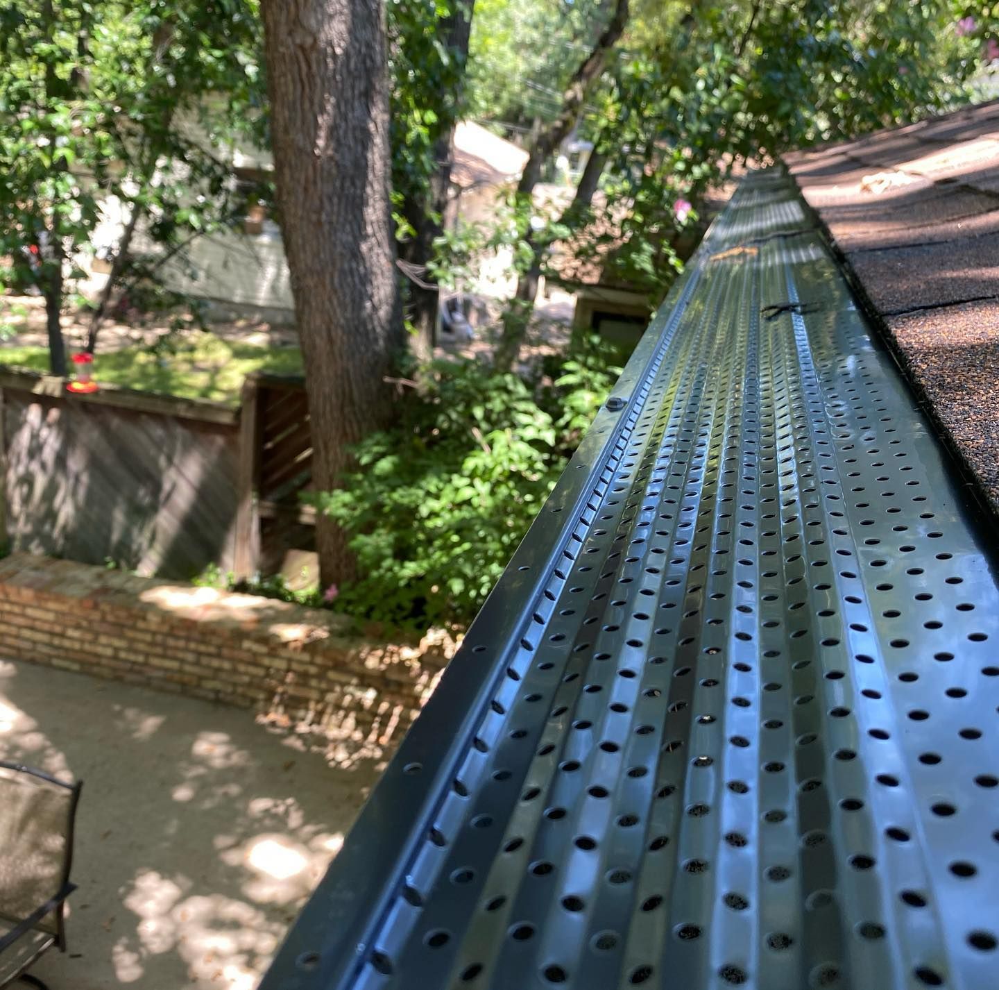 A gutter with holes in it is sitting on top of a roof.