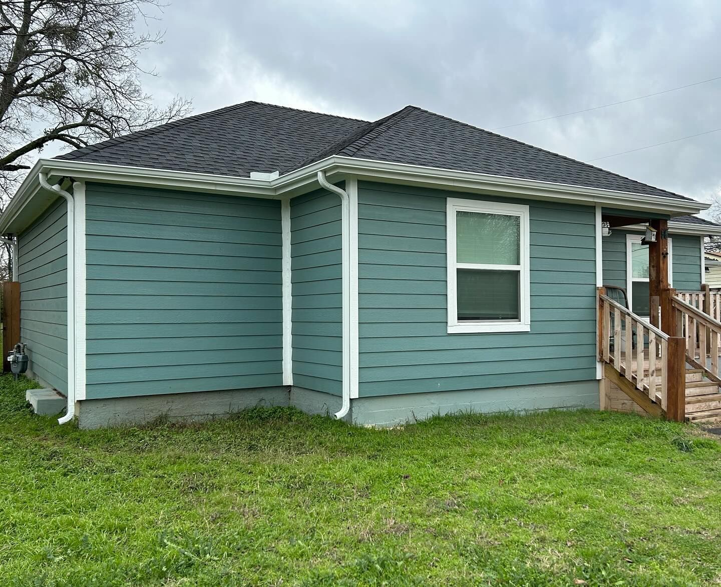 A small blue house with a black roof is sitting on top of a lush green lawn.