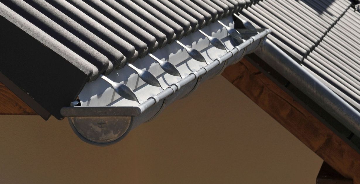 Gray tiled roof with a dark gutter and round exterior light beneath the eaves