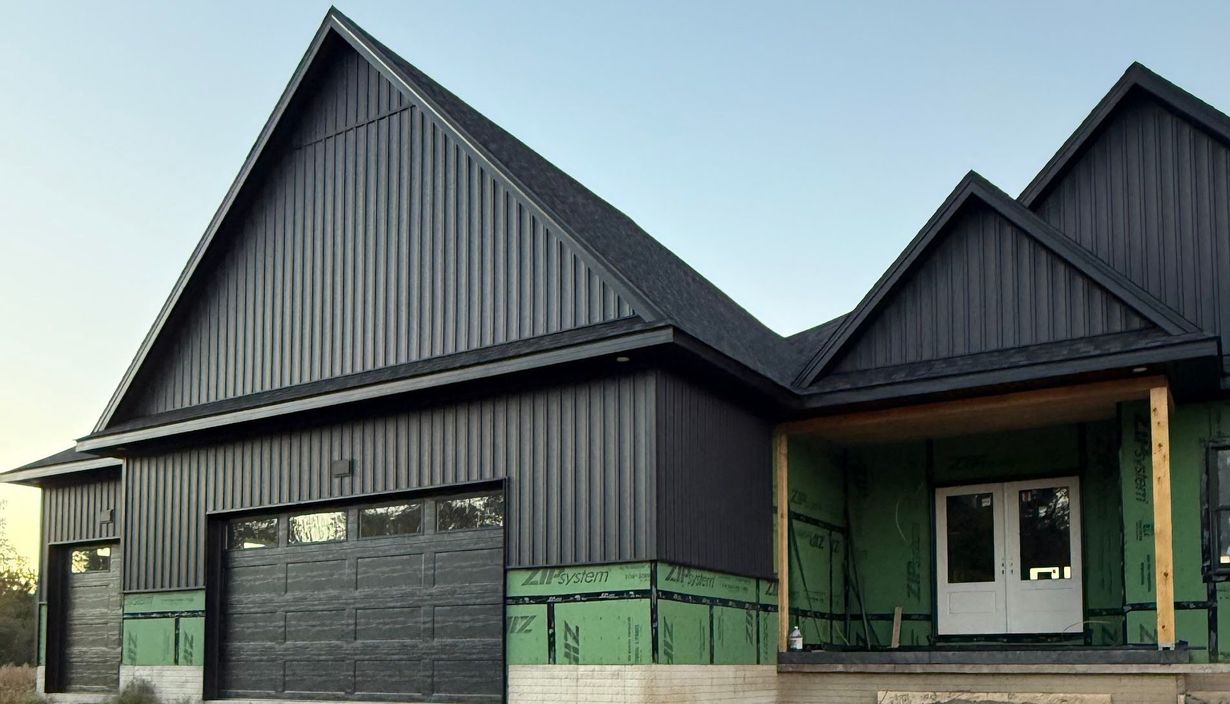 New dark gray house exterior with steep gabled roof and attached garage
