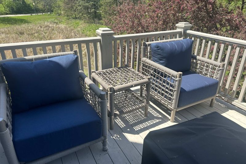 There are two chairs and a table on the deck.