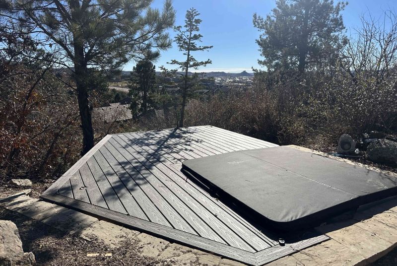 A hot tub is sitting on top of a wooden deck surrounded by trees.