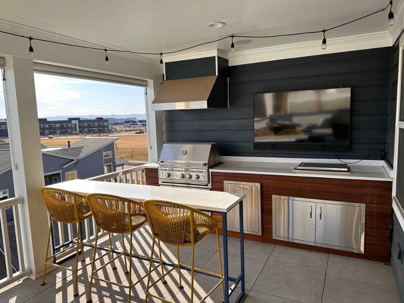 A porch with a grill , table , chairs and a flat screen tv.