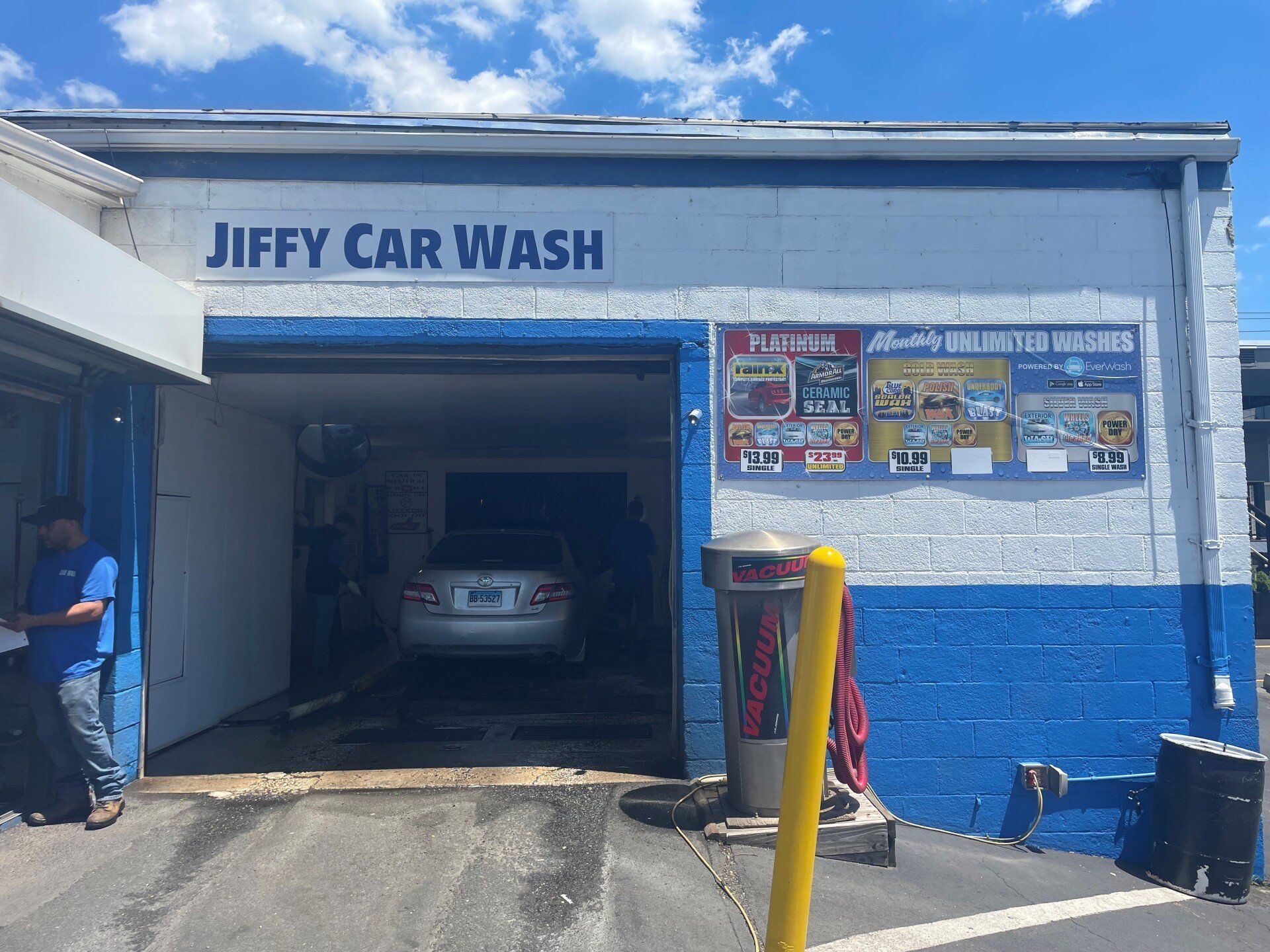 Jiffy Car Wash exterior with a car inside. Blue and white building, person on the left.