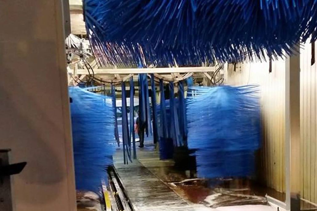 Blue car wash brushes inside a car wash bay.