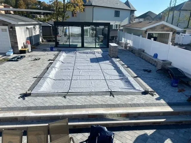 Backyard patio under construction with covered rectangular slab and tools around the edges