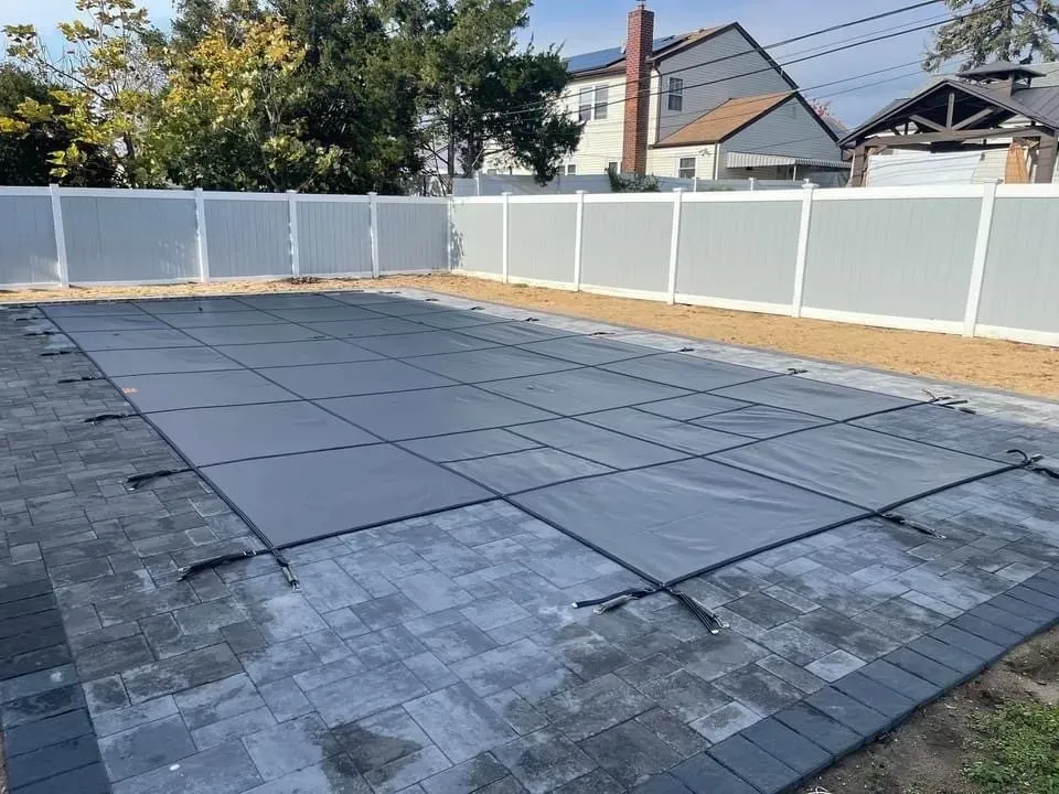 Flat rooftop deck under construction with dark waterproof panels and a white vinyl privacy fence 주변.