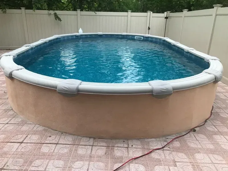 Round above-ground pool with blue water in a fenced backyard