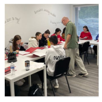 a man in a nasa shirt talks to a group of students