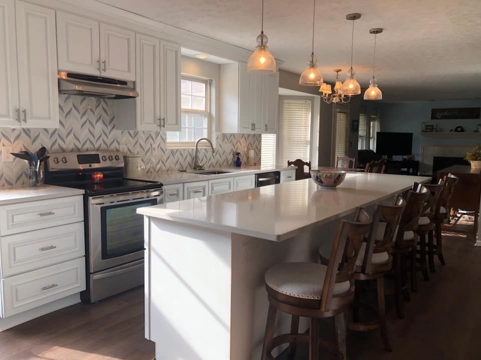 A kitchen with white cabinets, stainless steel appliances, and a large island.