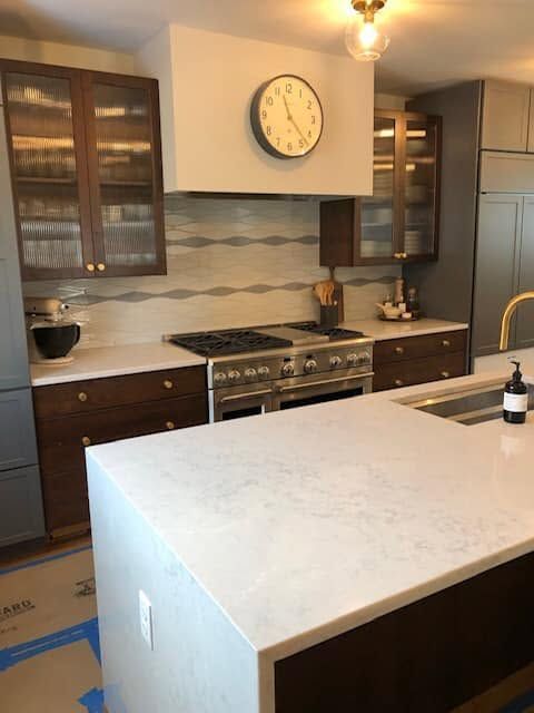A kitchen with a clock on the wall above the stove