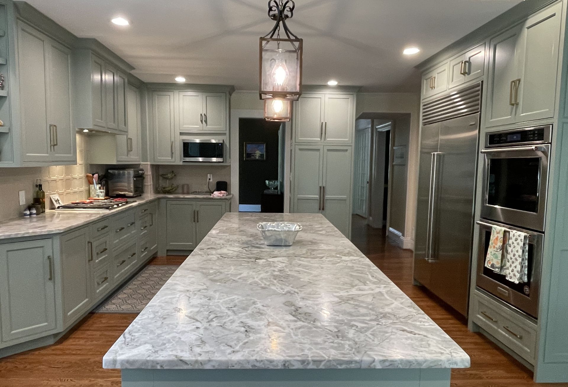A kitchen with a large island in the middle and stainless steel appliances.