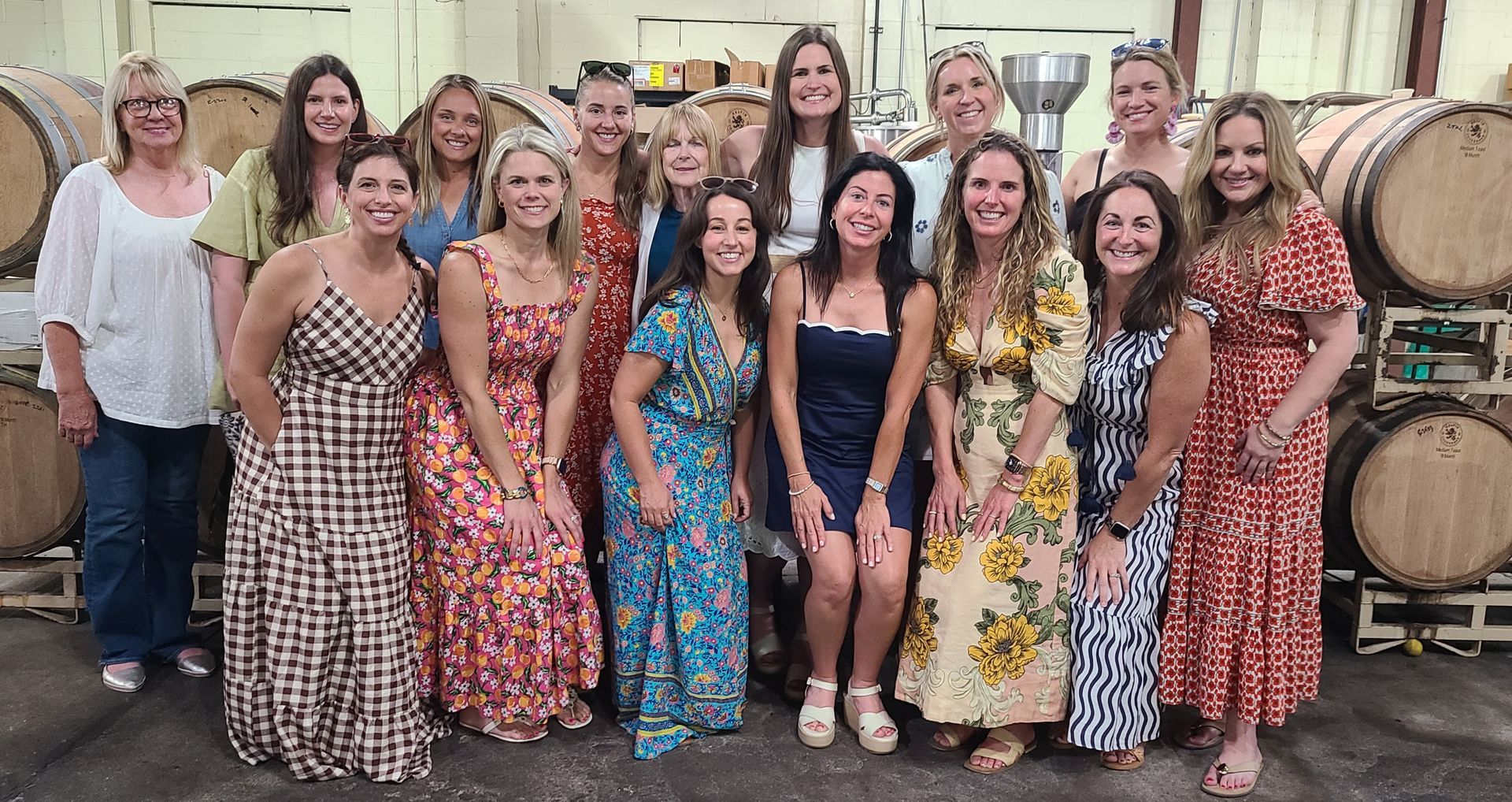 Group of women in colorful patterned dresses posing together indoors at a celebration.