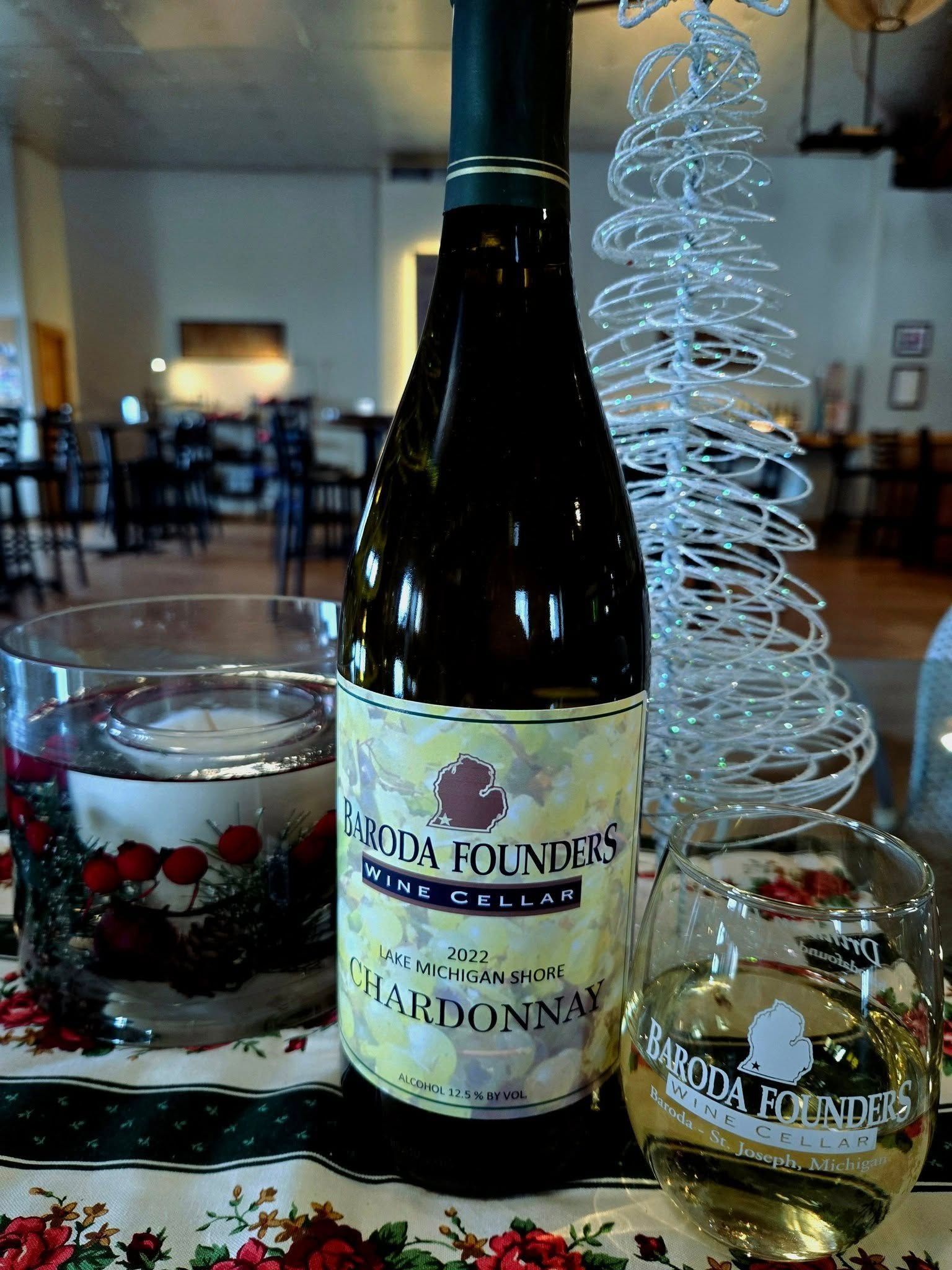 Wine bottle with glasses and a white wire Christmas tree centerpiece on a table