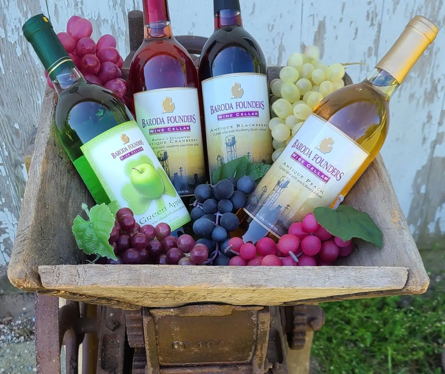 Wine bottles nestled among grapes in a rustic wooden cart outdoors