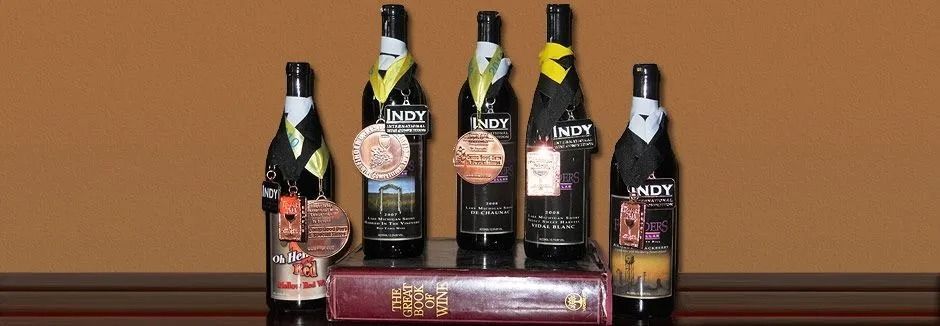 Assorted wine bottles displayed on a shelf with a purple gift box in front.