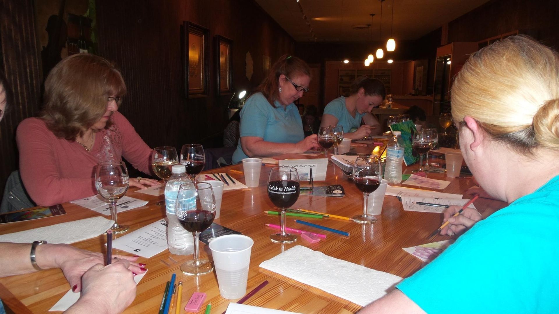 People seated around a dining table in a dimly lit restaurant, sharing a meal and drinks.