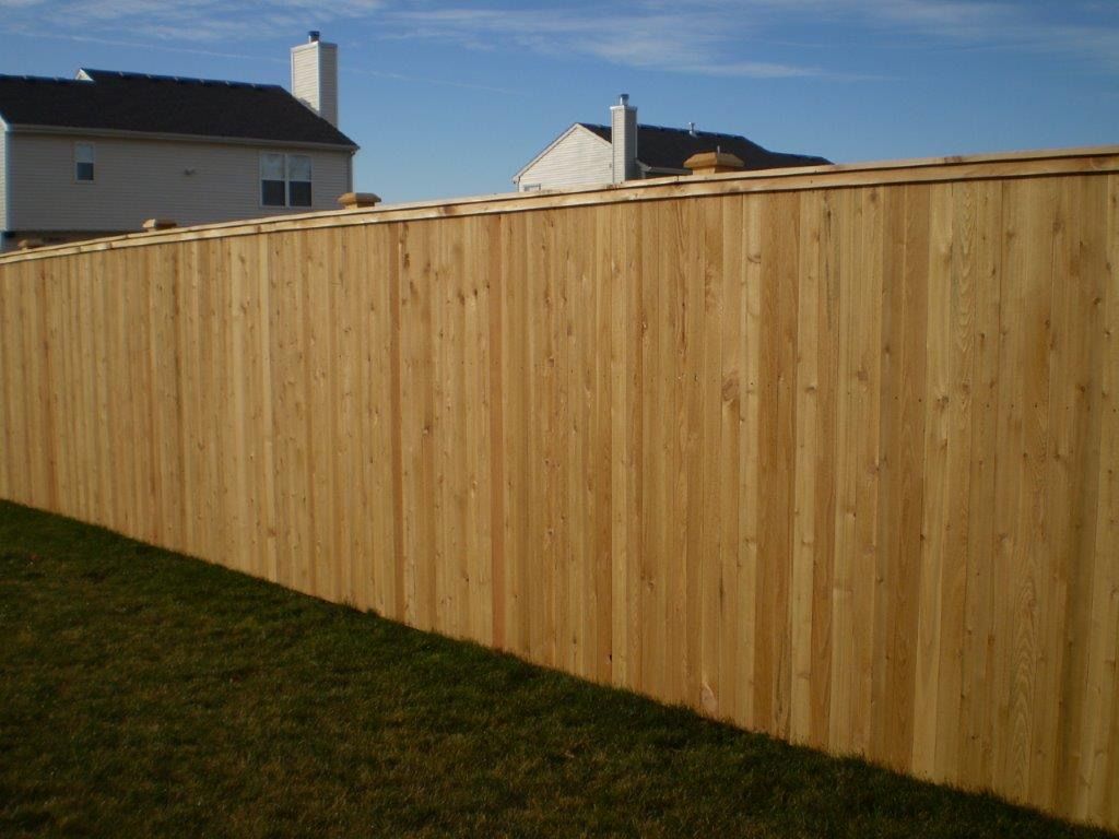 Wooden privacy fence in front of a house on a sunny day.
