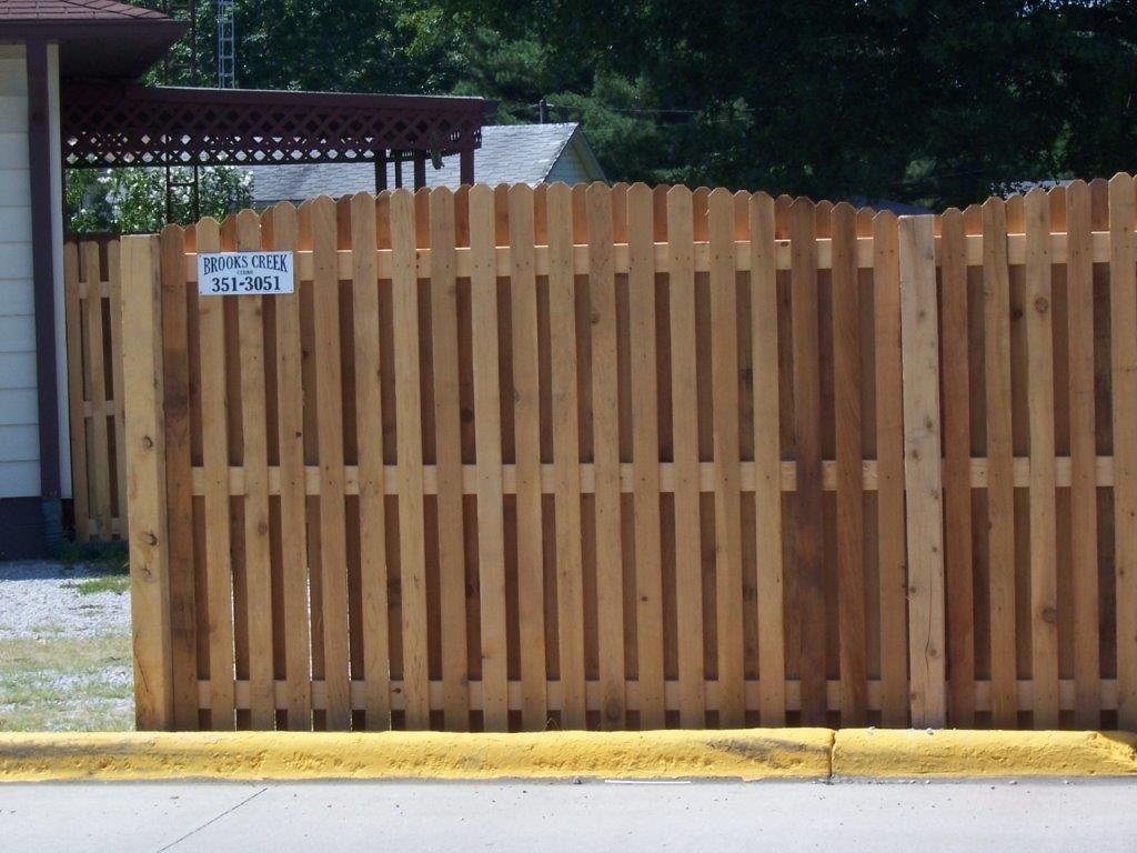Wooden picket fence with a sign, outdoors.