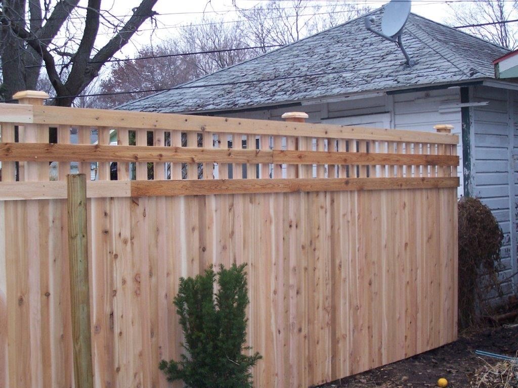 Wooden privacy fence with lattice top in front of a house.