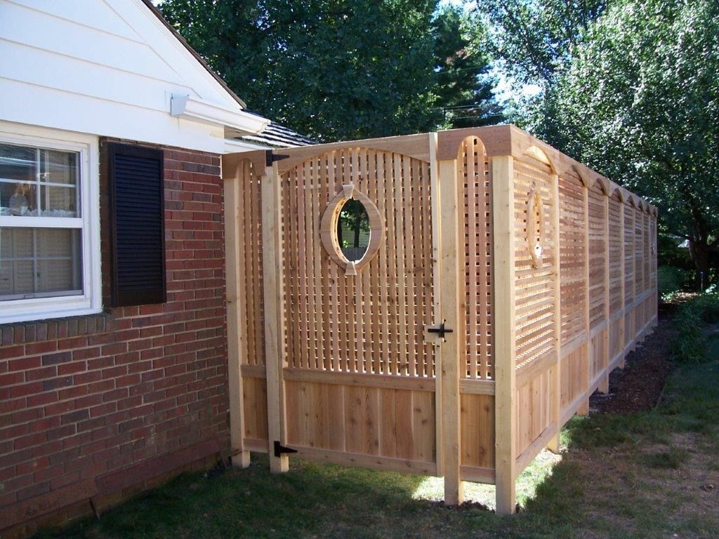 Wooden privacy fence with gate beside a brick house.