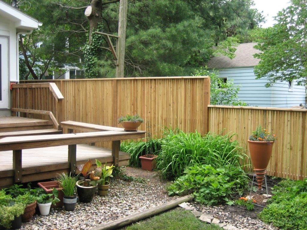 Wooden deck with ramp next to a gravel garden enclosed by a wooden fence.