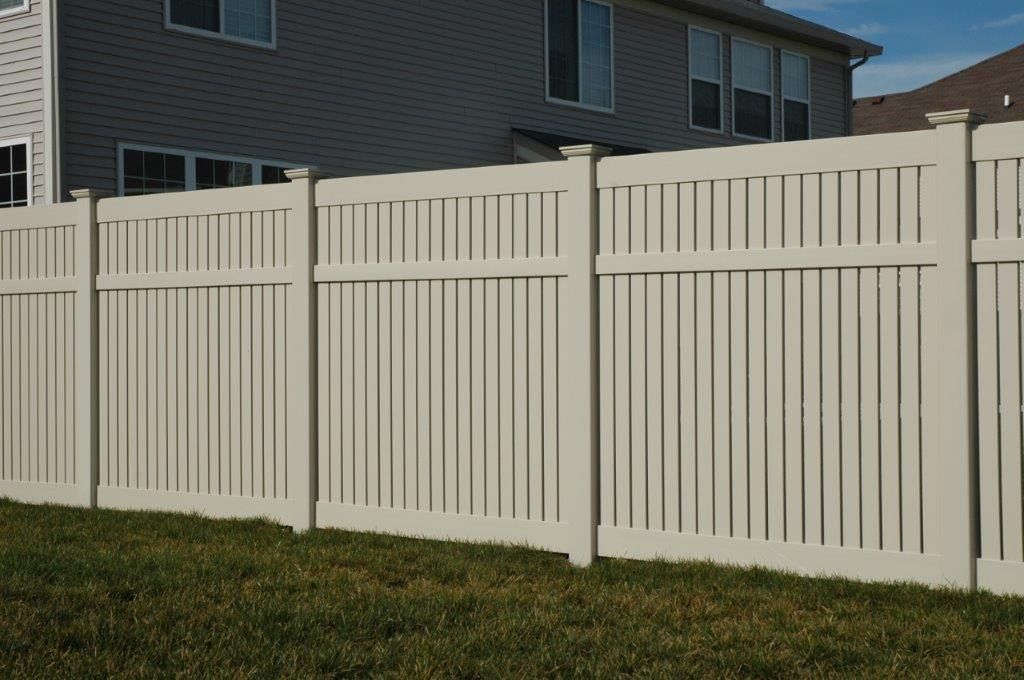 Beige vinyl fence enclosing a grassy yard, house in the background.