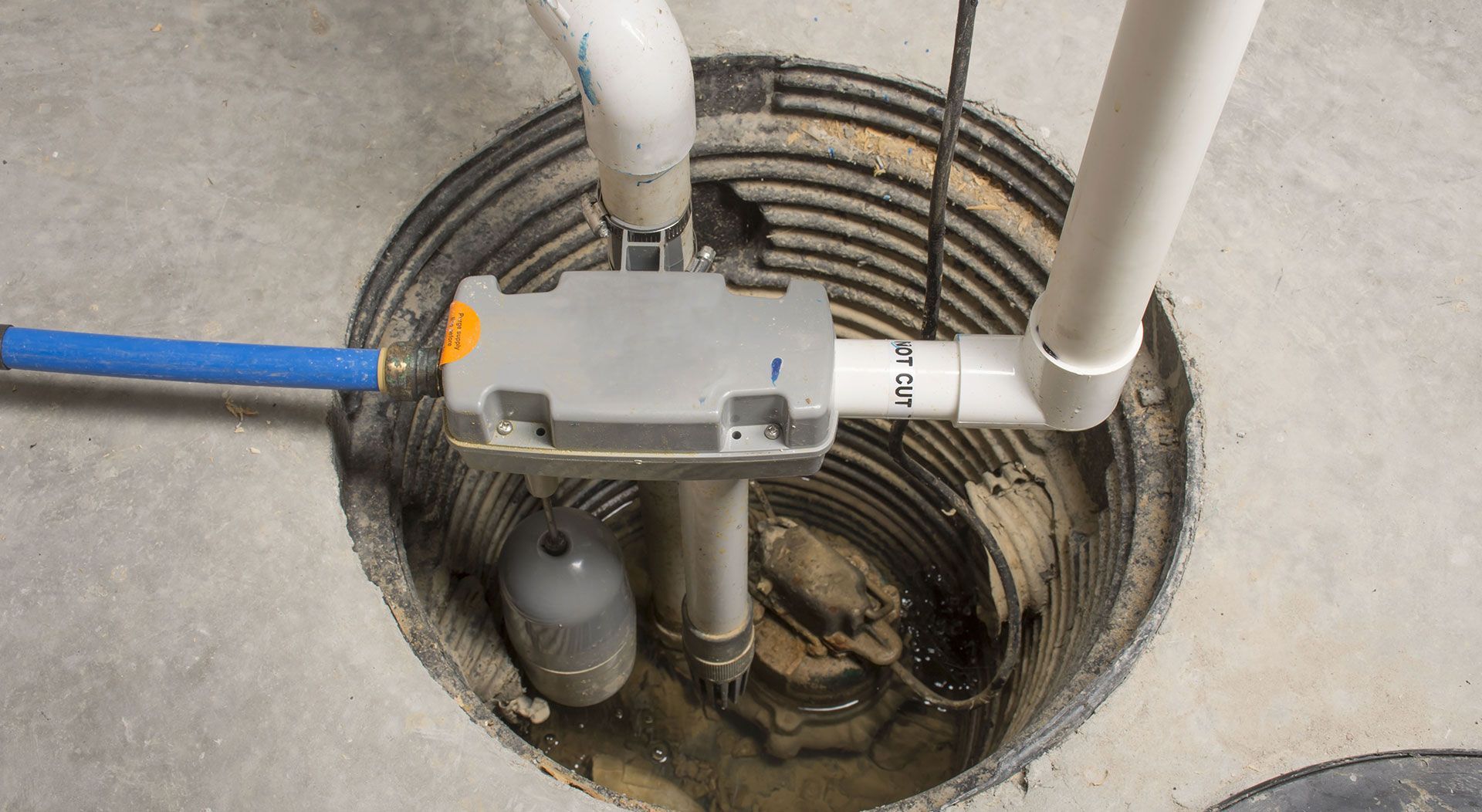 Sump pump system in concrete pit with pipes and float switch.