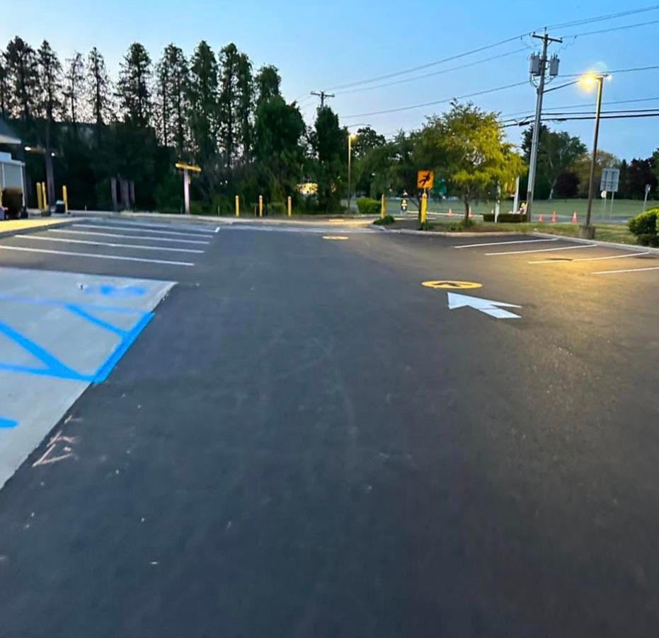 Asphalt road with crosswalk and trees in the distance under a blue sky, dusk.