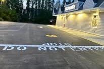 McDonald's restaurant with parking lot. Building is beige. Asphalt with painted white lettering.