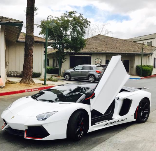 A white lamborghini aventador is parked on the side of the road
