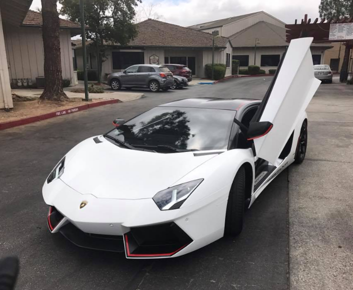 A white lamborghini is parked on the side of the road
