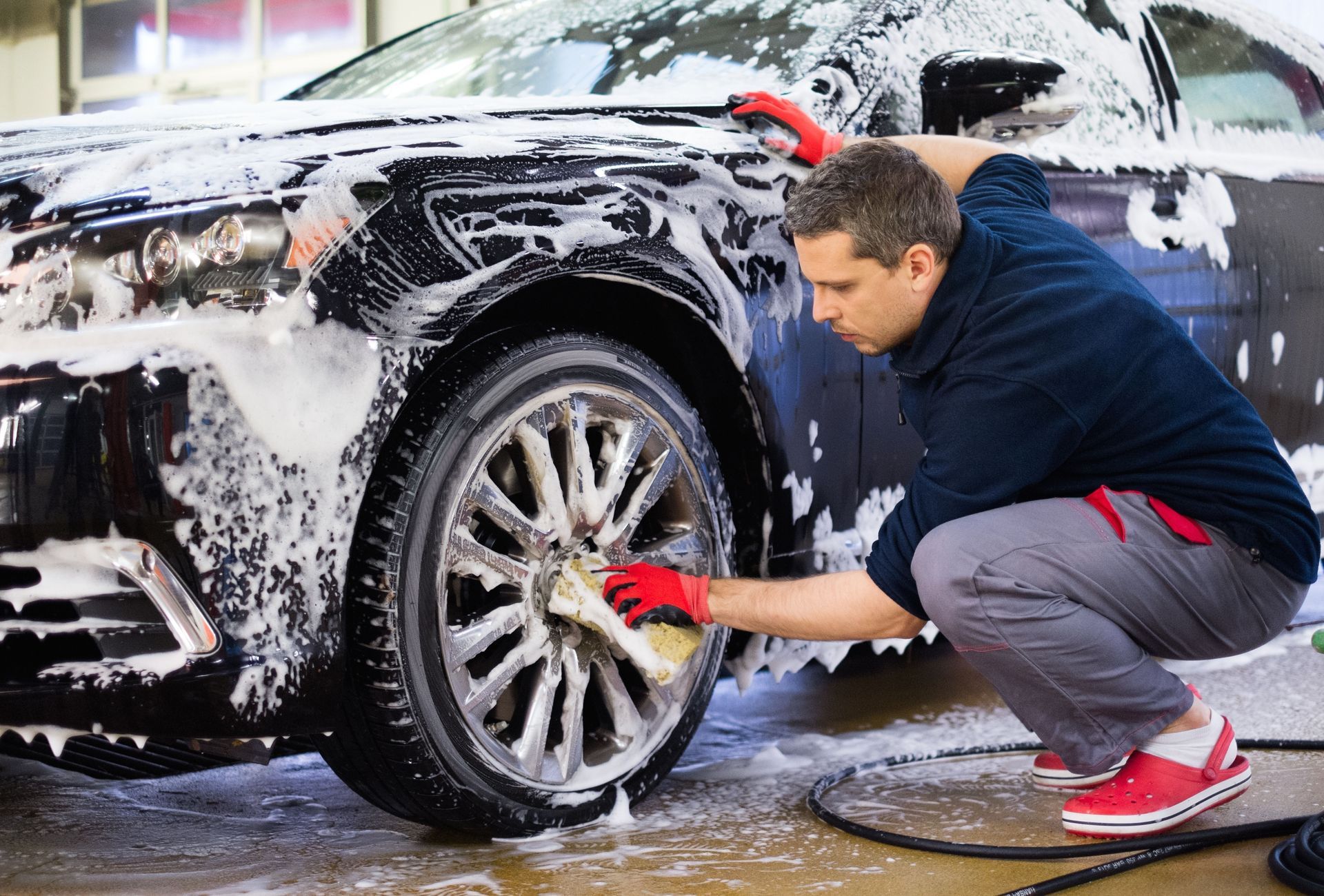 A man is washing a car with a sponge and foam.
