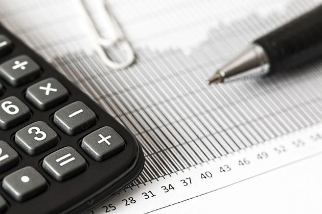Calculator and pen on financial paperwork with grid lines and numbers