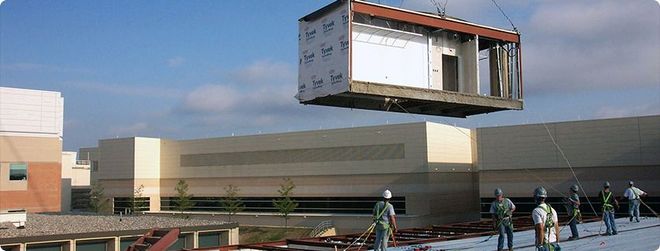 A row of unfinished concrete houses under construction on a dirt lot.