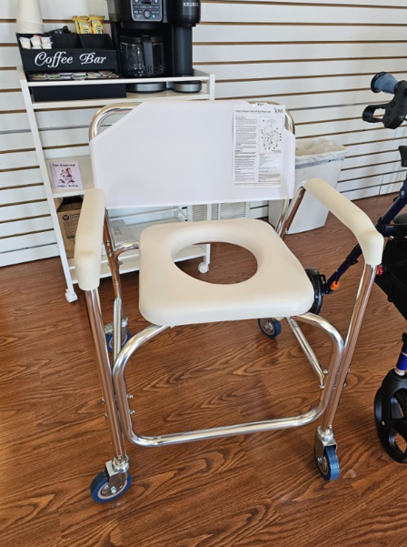 Shower chair with a cutout seat and armrests on wheels, indoors.