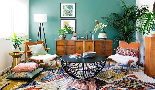 A living room with a rug , chairs, a coffee table and a green wall
