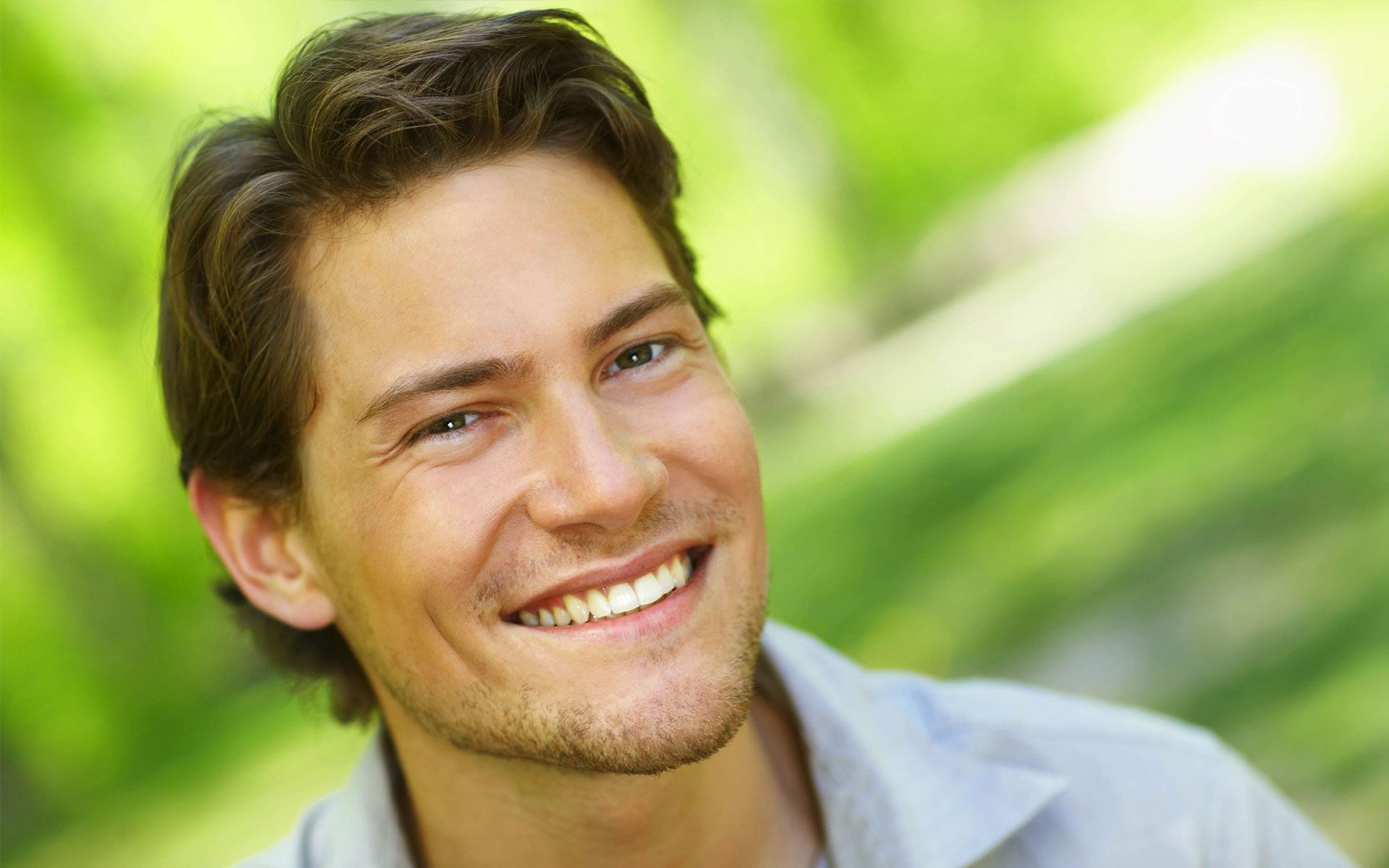A close up of a man smiling in a park.