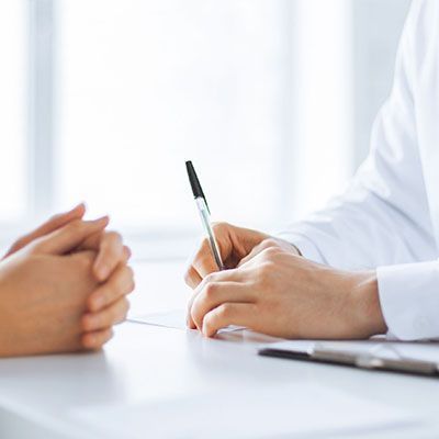 A doctor is sitting at a table talking to a patient.