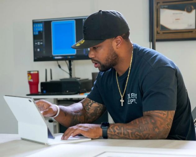 Man in a black cap using a tablet at a desk in a modern office