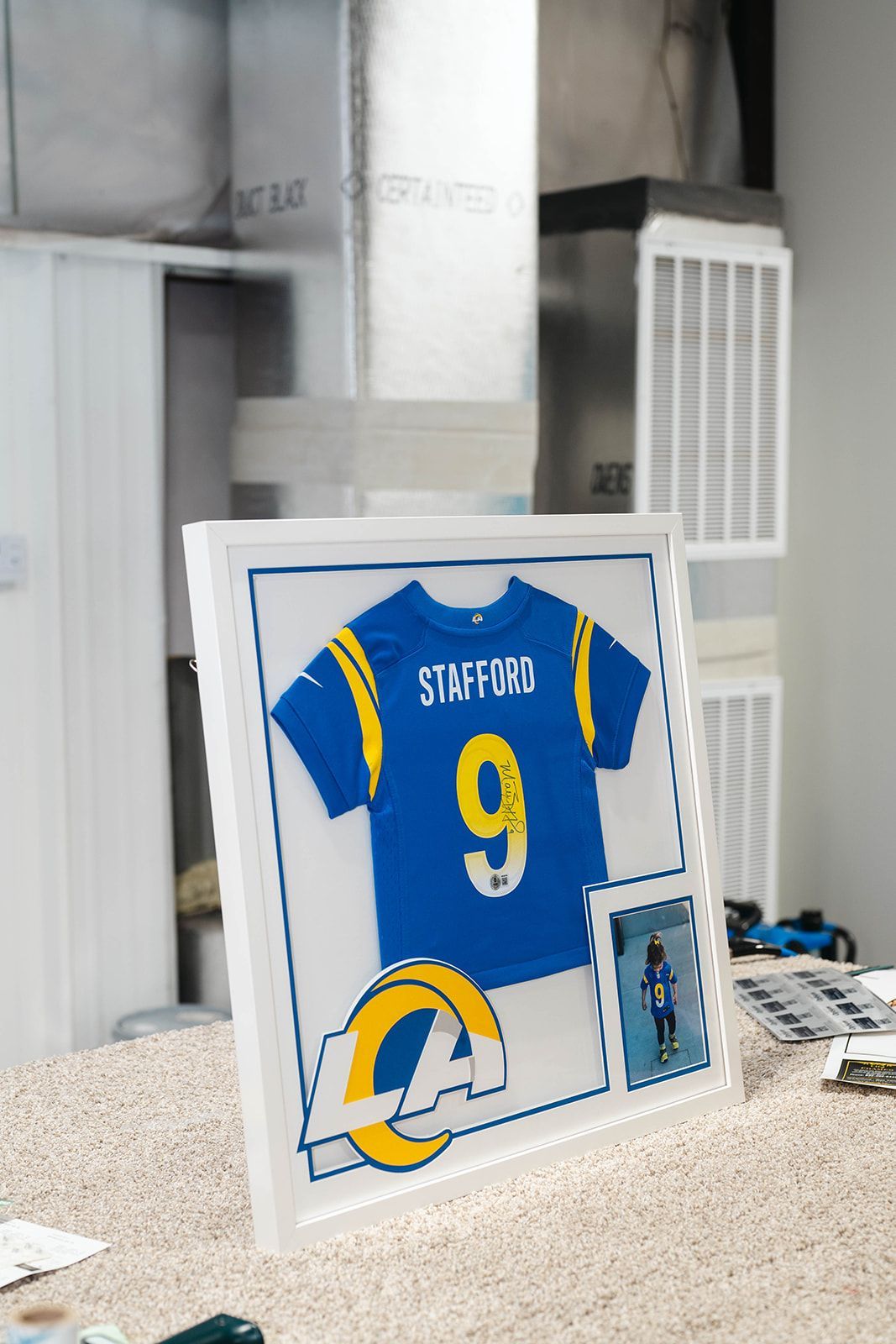 Framed blue-and-yellow St. Louis Rams jersey with number 9 displayed on a countertop.