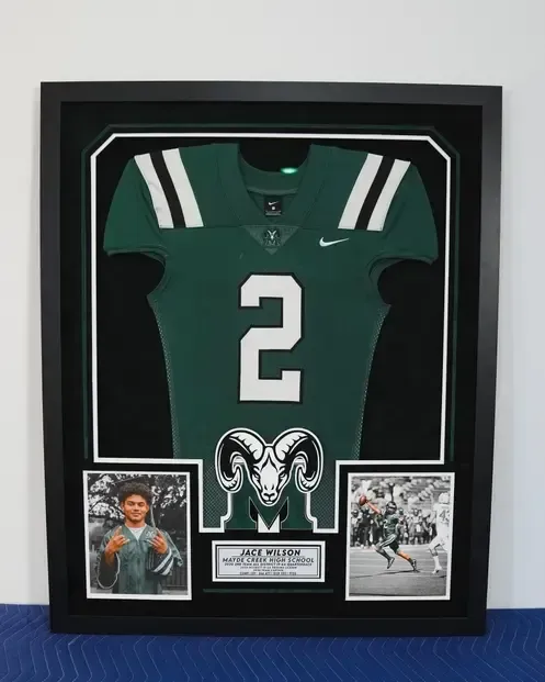 Framed green football jersey with number 2 and Penn State logo, flanked by two photos and a nameplate.