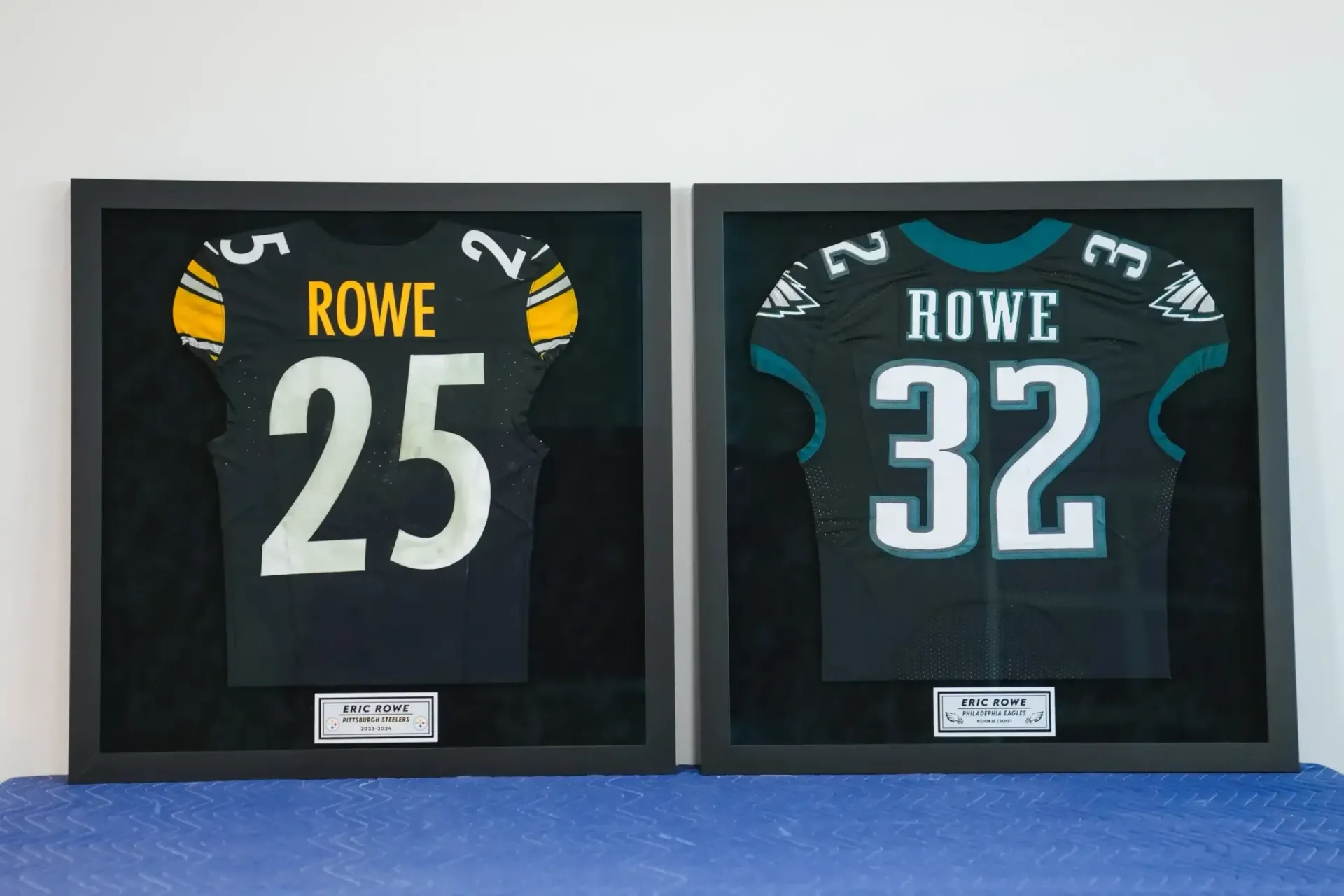 Framed football jerseys labeled Rowe 25 and Rowe 32 displayed side by side on a wall.
