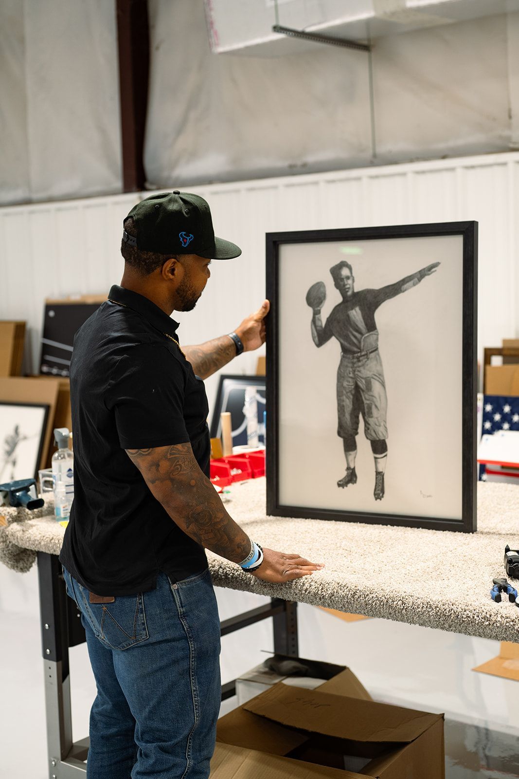 Man in a black cap and shirt framing a black-and-white basketball portrait in a studio workspace